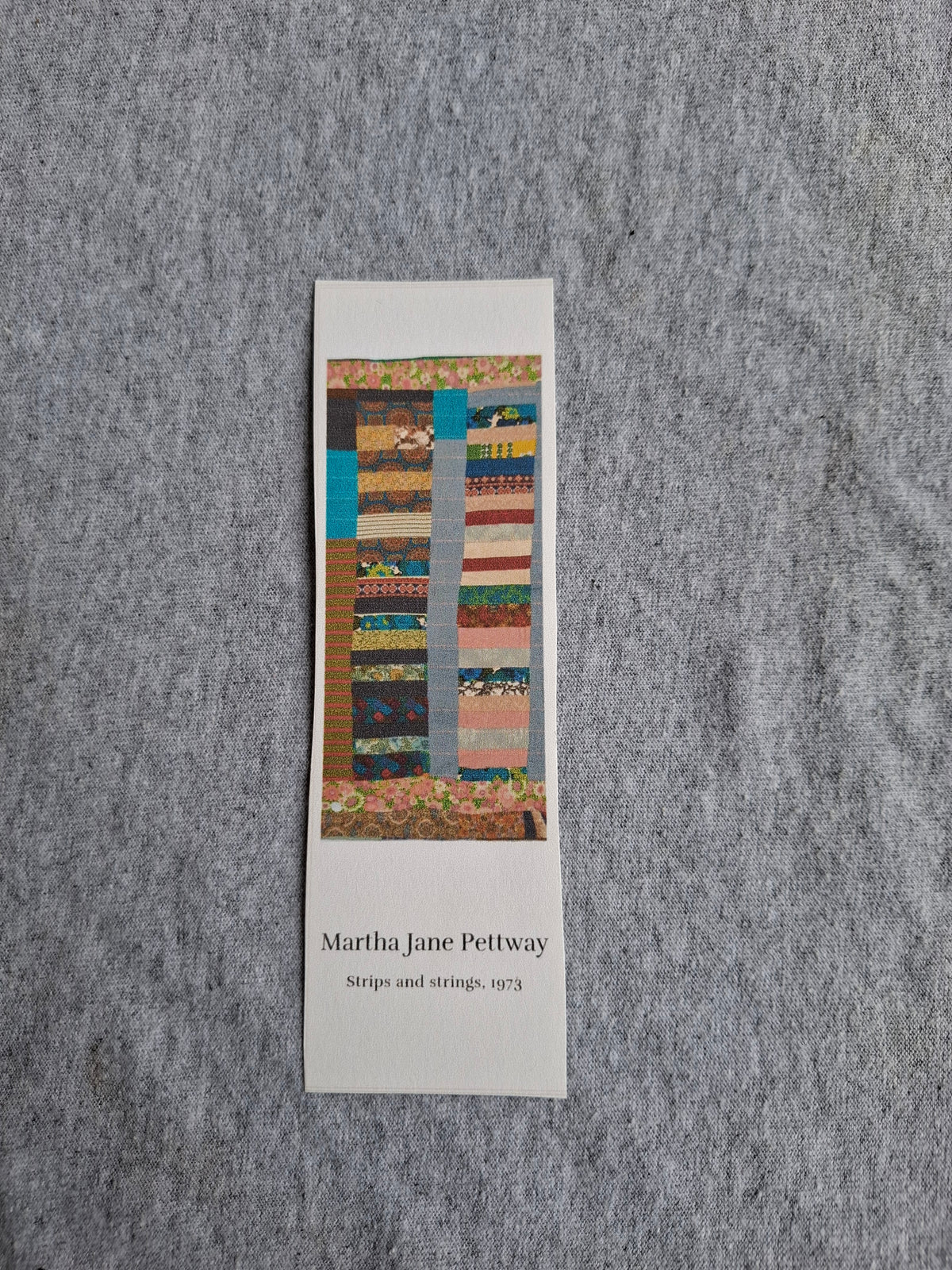 Front of heritage bookmark featuring Grandma Martha Jane Pettway's Strips and Strings quilt (1973), with colorful patterned fabric strips.